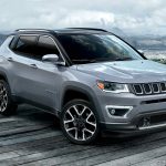 Image of a gray 2019 Jeep Compass parked on a cliff overlooking a lake.