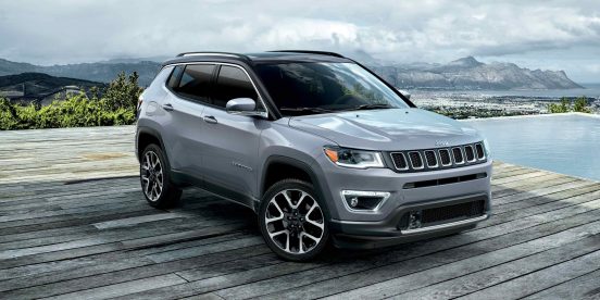 Image of a gray 2019 Jeep Compass parked on a cliff overlooking a lake.