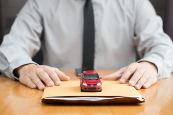 Image of a man with a tie sitting at a table with documents and a toy car.