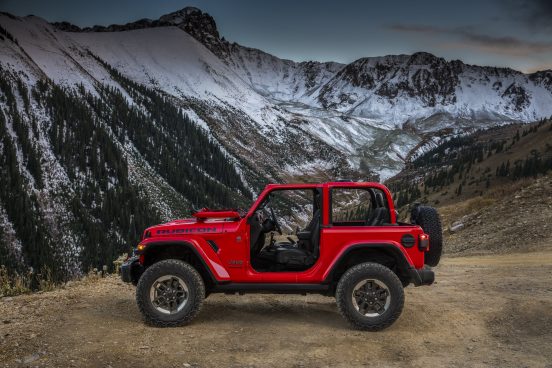 Image of a red 2019 Jeep Wrangler parked in front of a mountain landscape.