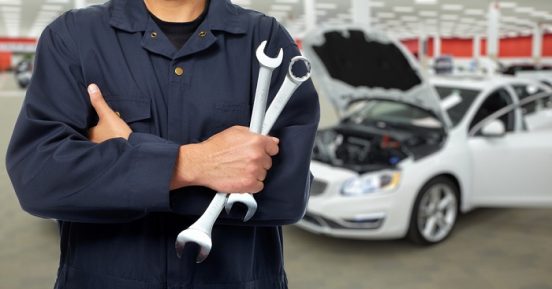 Image of a mechanic holding two wrenches with his arms crossed.