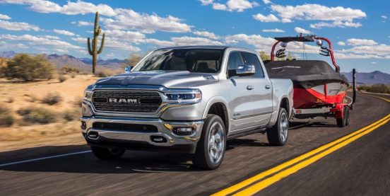 Image of a silver 2019 RAM 1500 towing a boat on a desert highway.