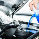 Jeep service technician refilling windshield wiper fluid